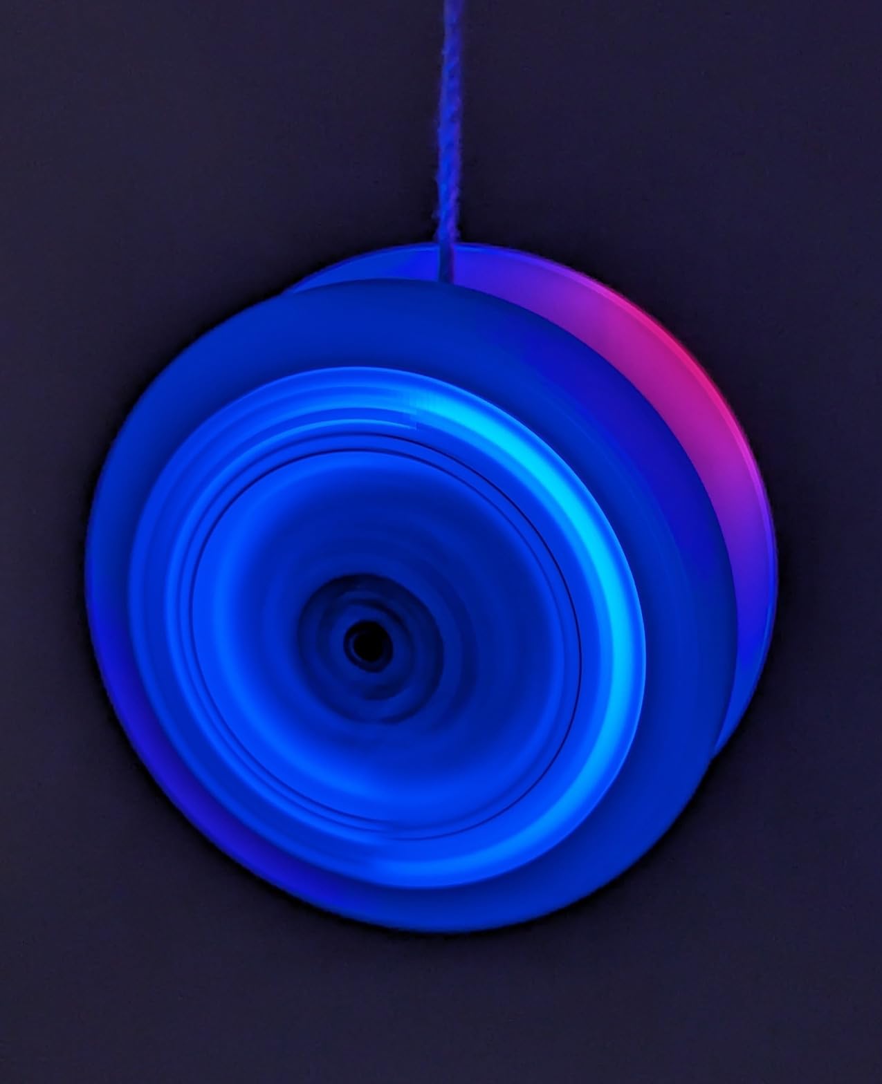 Yomega light-up yo-yo glowing blue while spinning in a dark room